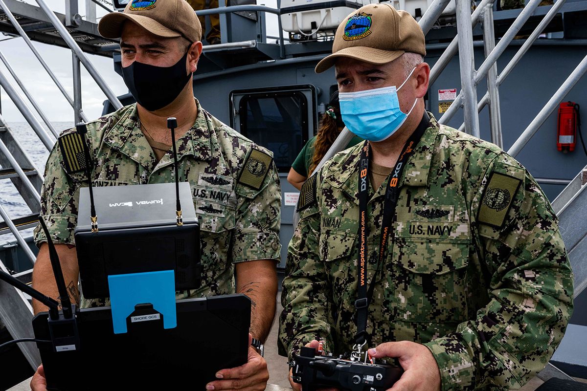 Two electronic technicians pilot an unmanned aerial vehicle.