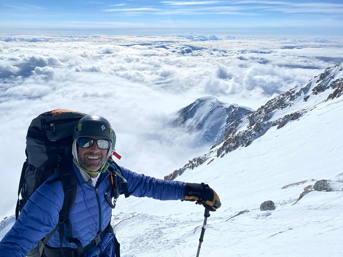 team member posing on top of the mountain