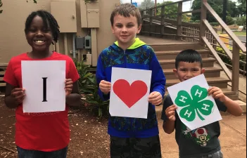 Three children holding drawings