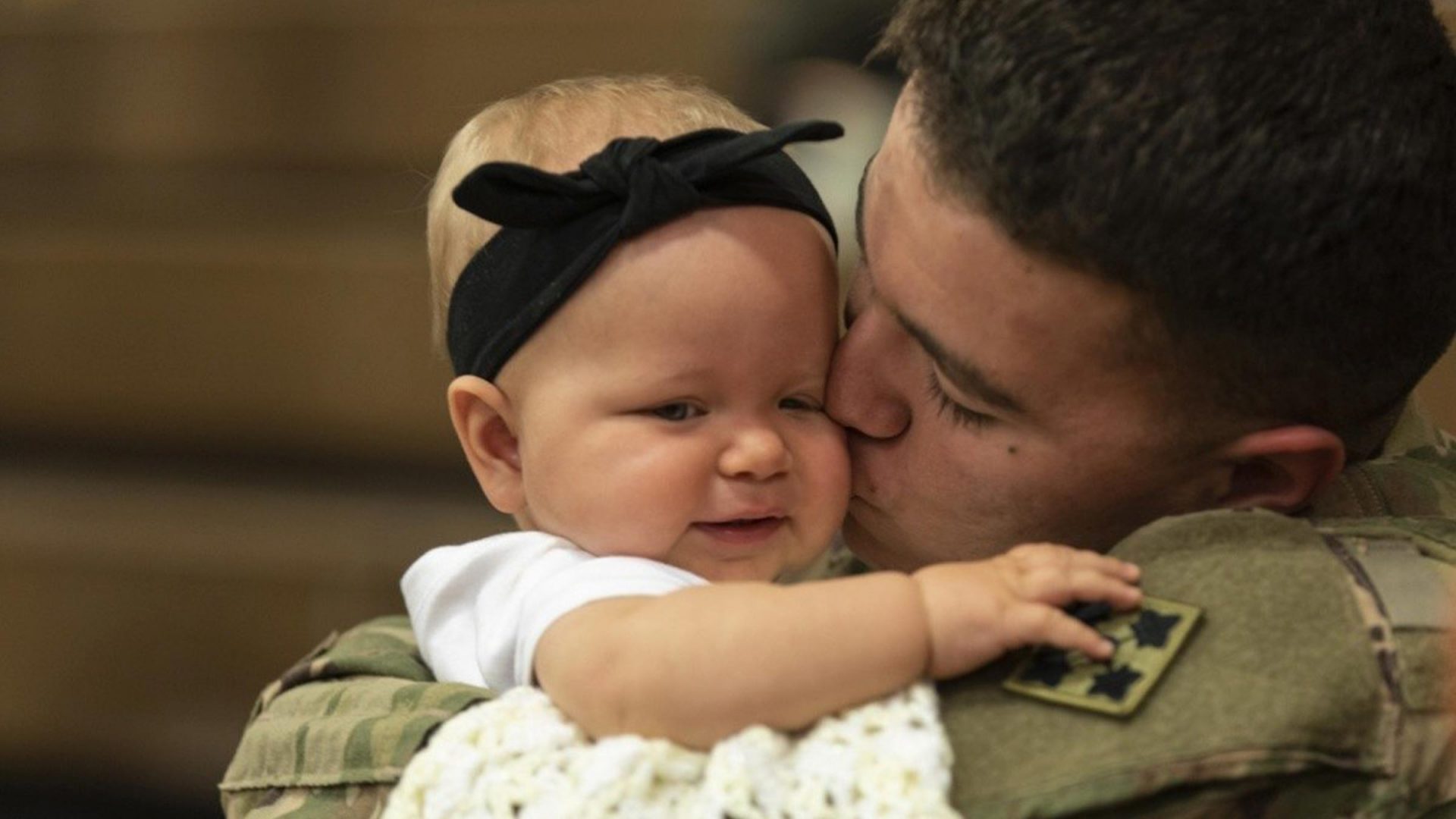 A military father kissing a baby