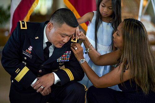 Wife adjusting military spouse's uniform.