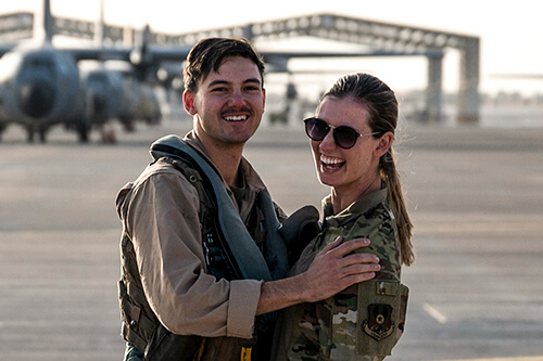 Military spouses hugging and smiling at the camera